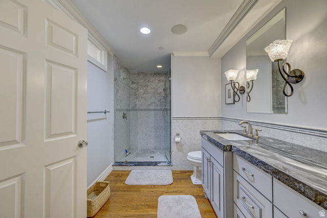 9699 Bypass Road, Unit 5 Alta, UT 84092 - Photo 40 of 54 Bathroom featuring a glass-enclosed shower with tiled walls and floor, a vanity with a dark stone countertop, an undermount sink, and wood-finish flooring