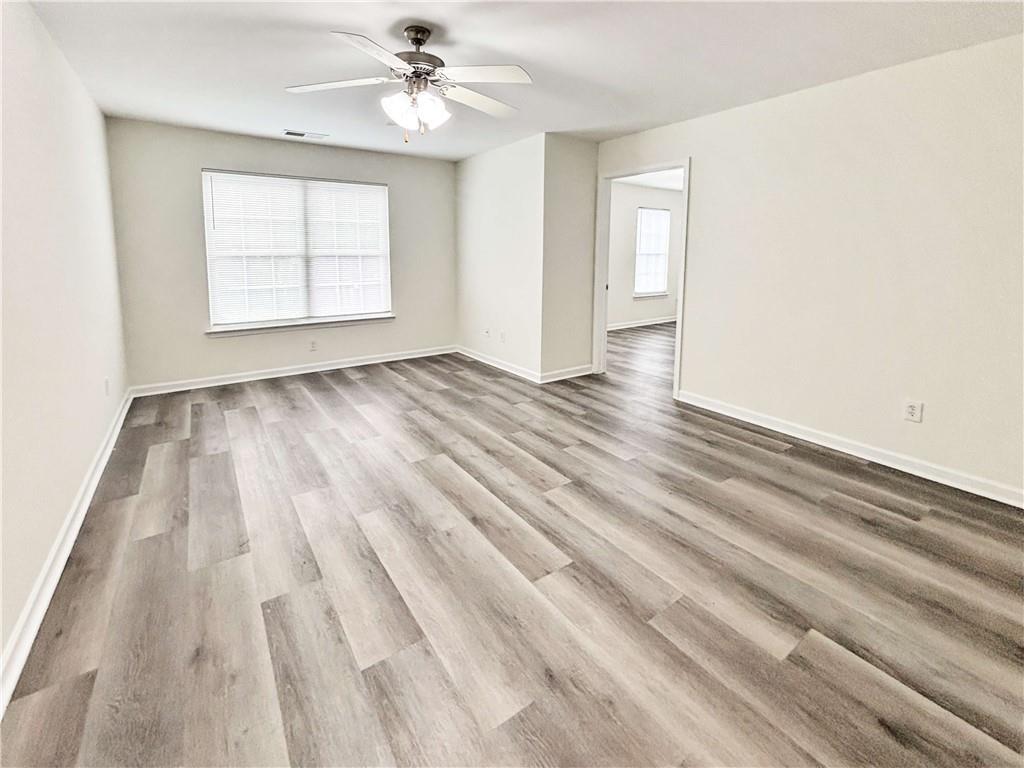 1400 Stonehaven Circle, Unit 1402 Cartersville, GA 30121 - Photo 4 of 23 an empty room with wooden floor chandelier fan and windows