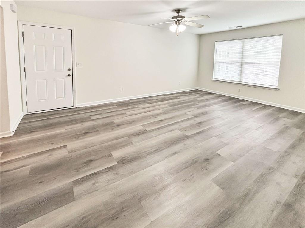 1400 Stonehaven Circle, Unit 1402 Cartersville, GA 30121 - Photo 6 of 23 an empty room with wooden floor chandelier fan and windows