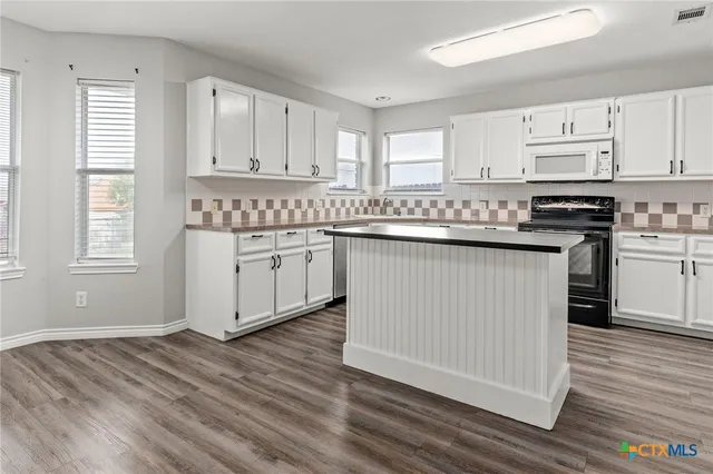 a kitchen with stainless steel appliances granite countertop a stove a sink and white cabinets