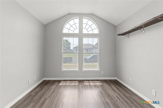 an empty room with wooden floor and windows