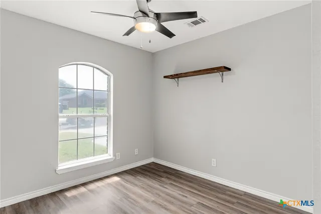 an empty room with windows and fan