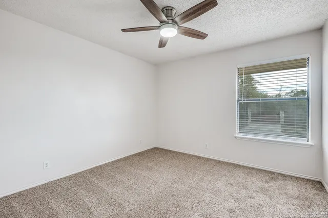 an empty room with a window and a ceiling fan