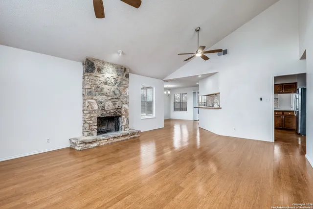 a view of empty room with fireplace and wooden floor