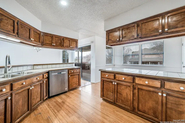 a kitchen with stainless steel appliances granite countertop a sink and wooden cabinets