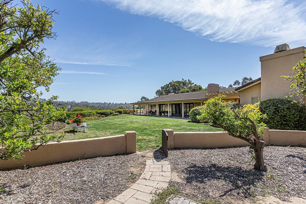 16854 Los Morros Rancho Santa Fe, CA 92067 - Photo 33 of 40 a view of a patio with couches and a table and chairs under an umbrella