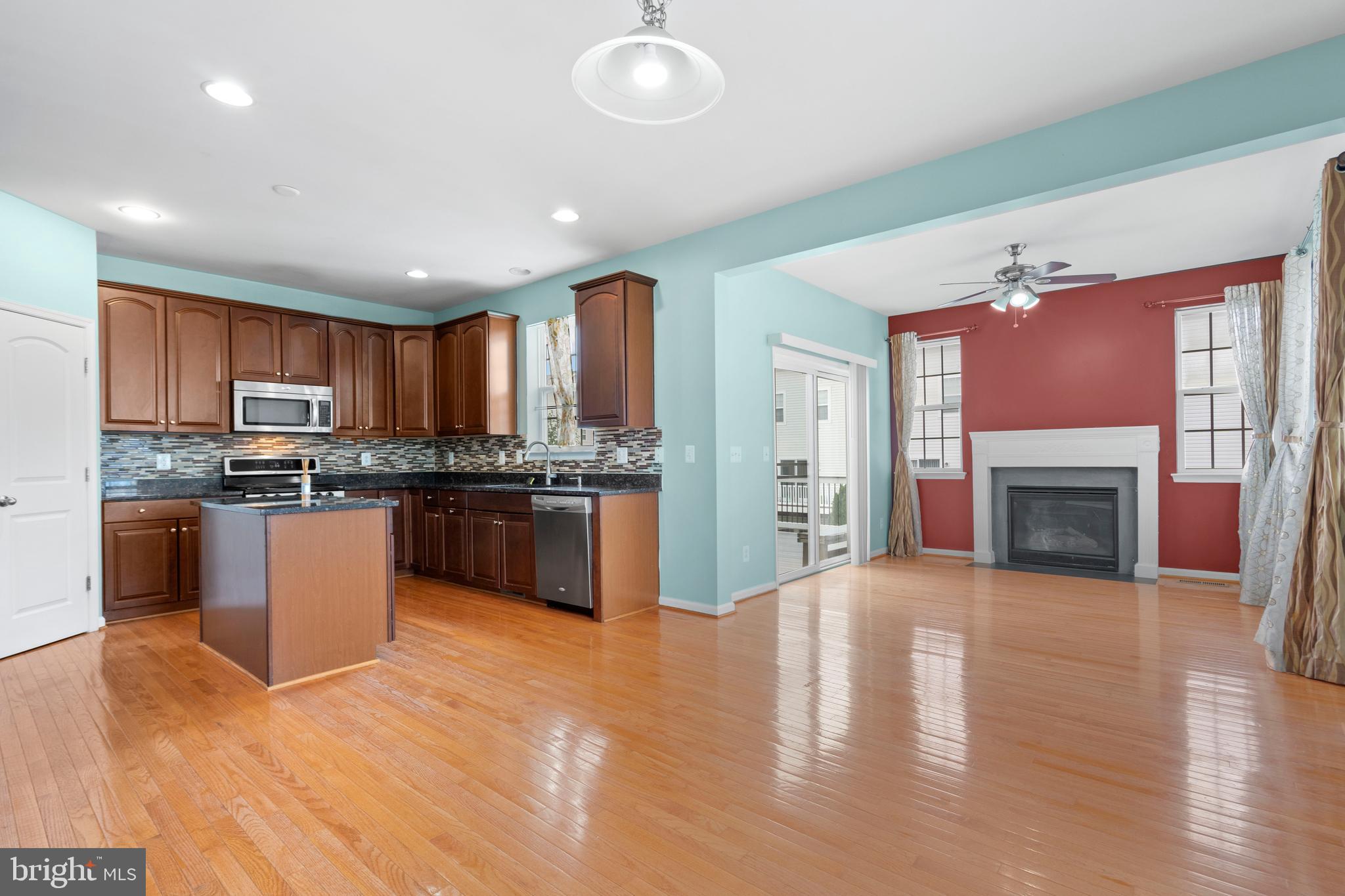 22667 Flowing Spring Square Brambleton, VA 20148 - Photo 7 of 39 a kitchen with granite countertop a stove top oven a sink dishwasher and a fireplace with wooden floor