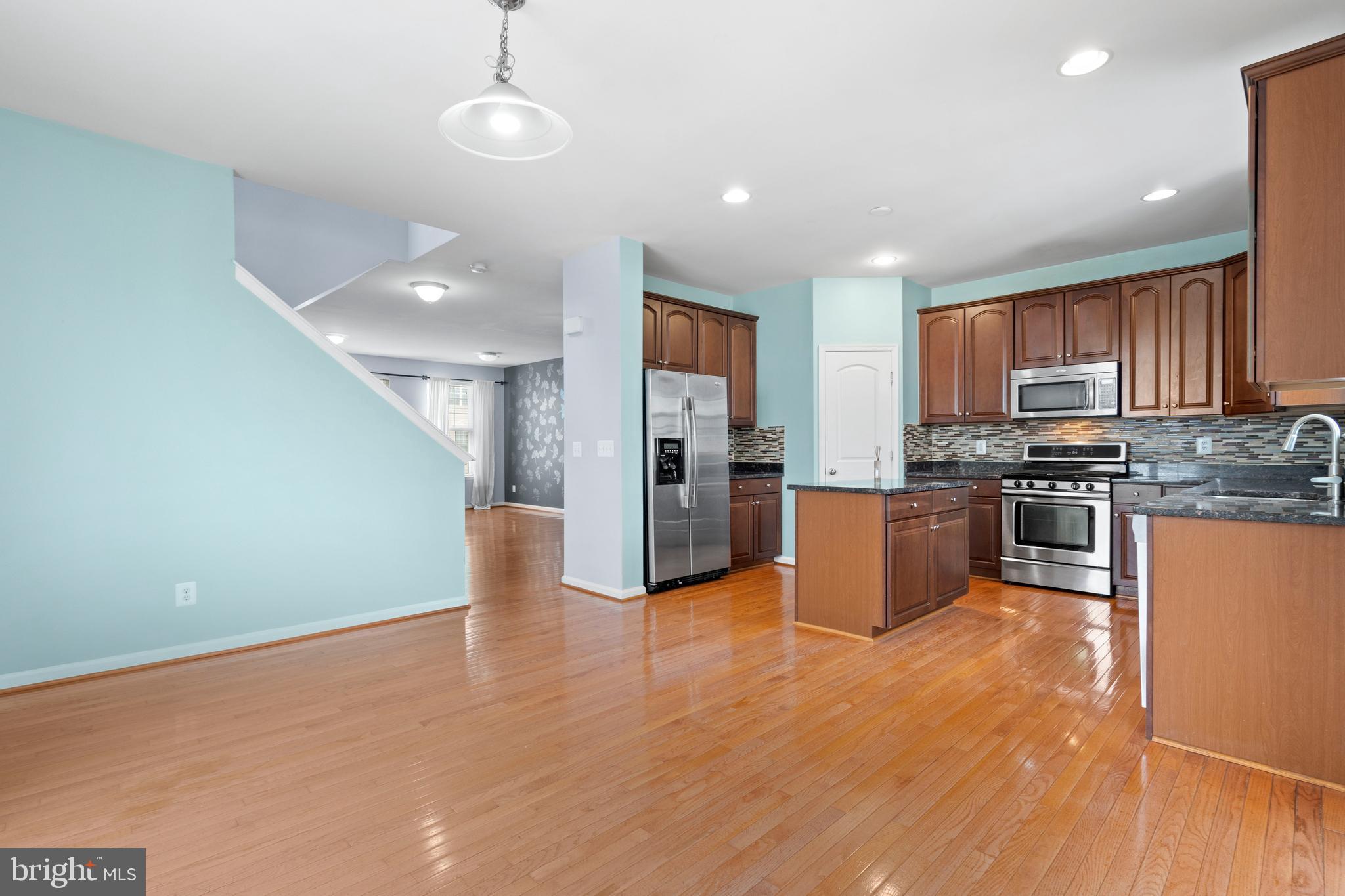 22667 Flowing Spring Square Brambleton, VA 20148 - Photo 8 of 39 a kitchen with stainless steel appliances granite countertop a refrigerator a stove top oven a sink and dishwasher with wooden floor