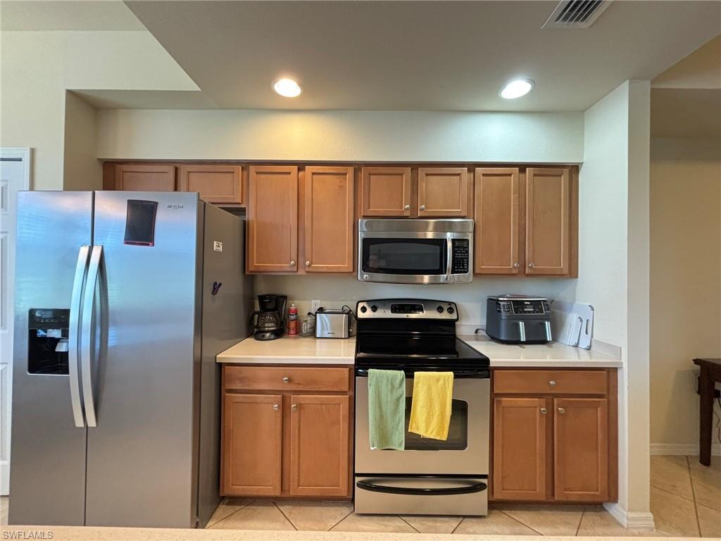 10341 Heritage Bay Boulevard, Unit 1922 Naples, FL 34120 - Photo 7 of 36 a kitchen with stainless steel appliances a refrigerator a stove a microwave and cabinets