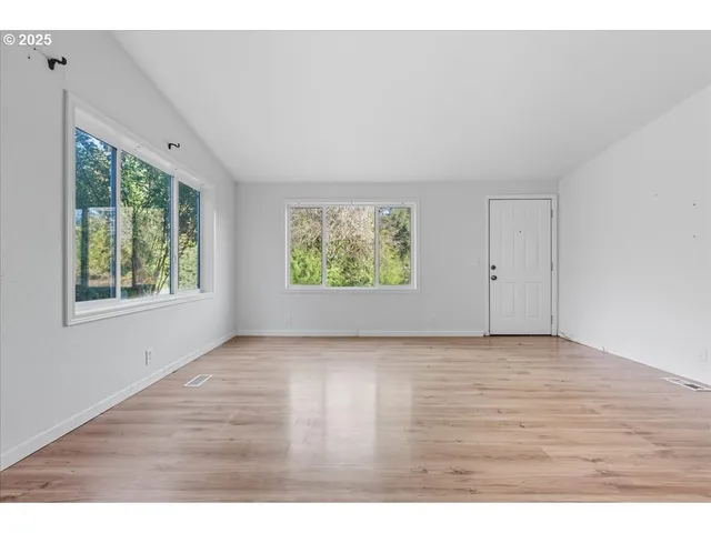 a view of an empty room with wooden floor and windows