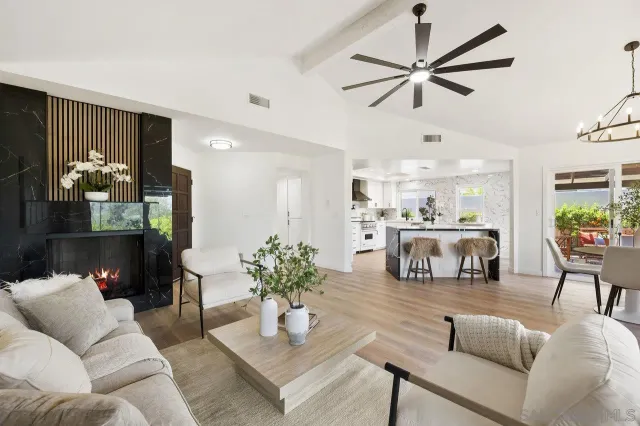 a living room with furniture kitchen view and a chandelier