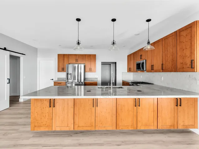 a kitchen with stainless steel appliances granite countertop a sink a refrigerator and a wooden floors