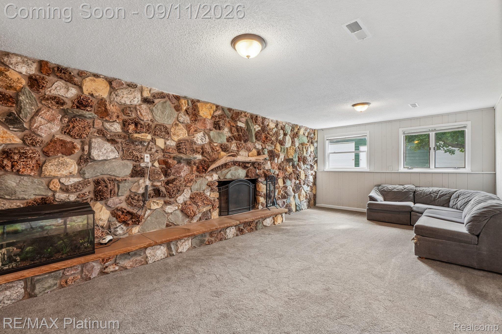 12126 Linden Road Linden, MI 48451 - Photo 20 of 38 Stone-clad fireplace wall with a hearth, wall-to-wall carpeting, and two windows