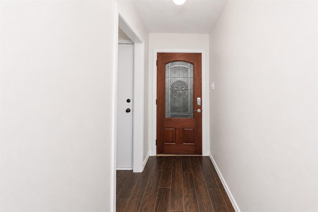 1001 Rosebud Drive Azle, TX 76020 - Photo 6 of 36 Entryway featuring a rich wood-finish door with decorative glass, dark wood-finish flooring, white walls, and bright overhead lighting