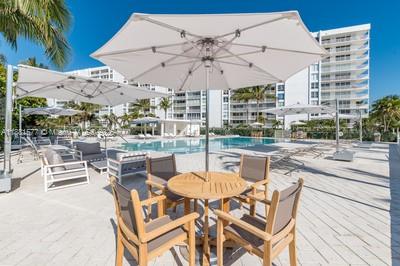 609 Ocean Drive, Unit 8G Key Biscayne, FL 33149 - Photo 27 of 44 a view of a patio with a table and chairs under an umbrella