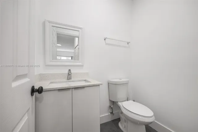 a bathroom with a granite countertop toilet a sink and mirror