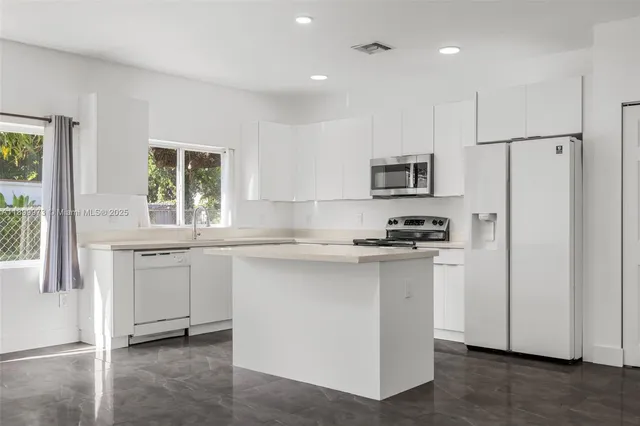 a kitchen with stainless steel appliances granite countertop a stove a sink and a refrigerator