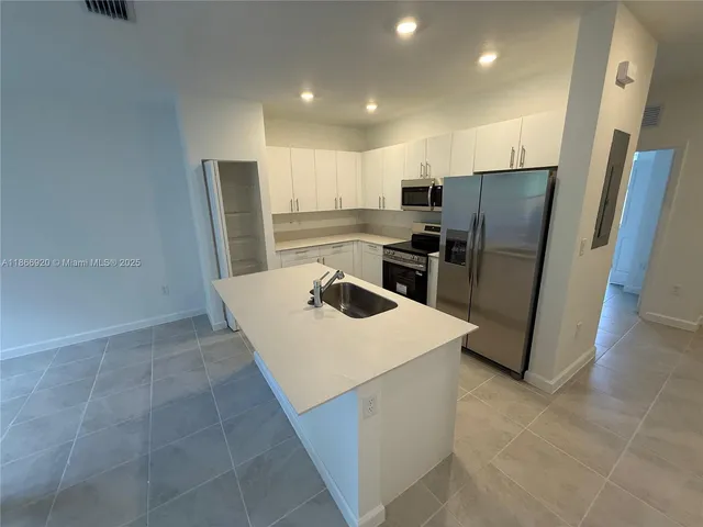 a kitchen with stainless steel appliances a refrigerator a stove a sink and a refrigerator