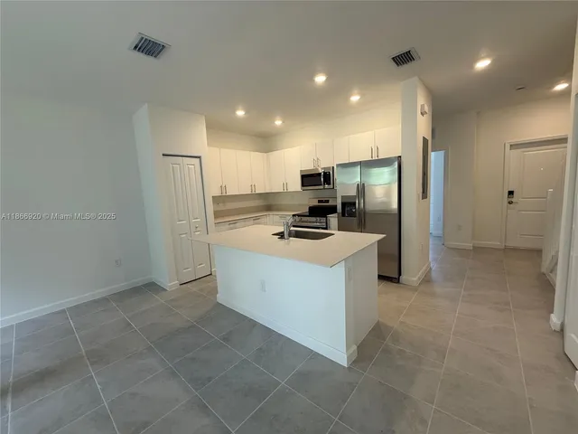 a kitchen with a refrigerator a stove top oven and a sink