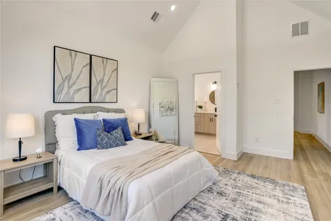 a bedroom with a large bed and wooden floor