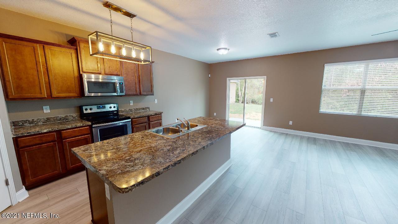 a kitchen with granite countertop wooden floors and wide window