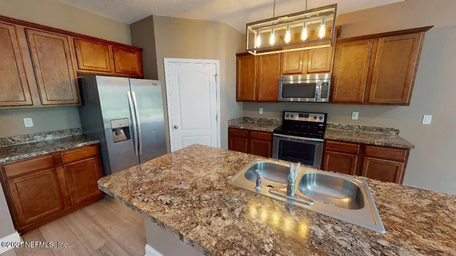 a kitchen with stainless steel appliances granite countertop a sink refrigerator stove and microwave