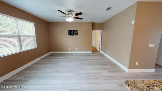 a view of empty room with wooden floor and fan