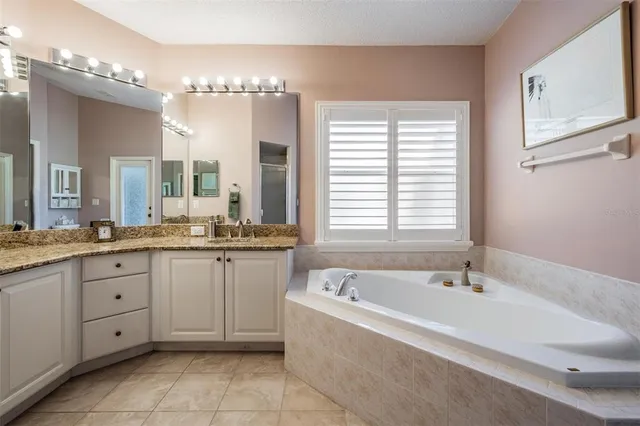 a spacious bathroom with a granite countertop tub a double vanity sink a vanity and a large mirror