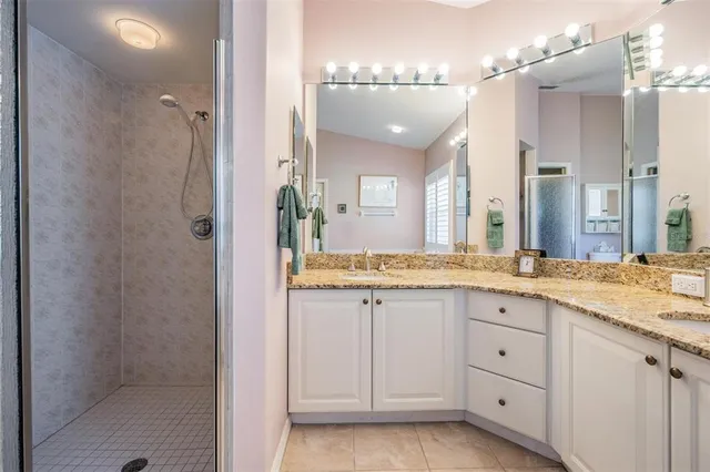 a spacious bathroom with a granite countertop sink a mirror and a shower