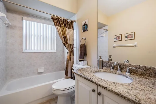 a bathroom with a granite countertop sink toilet and a bathtub