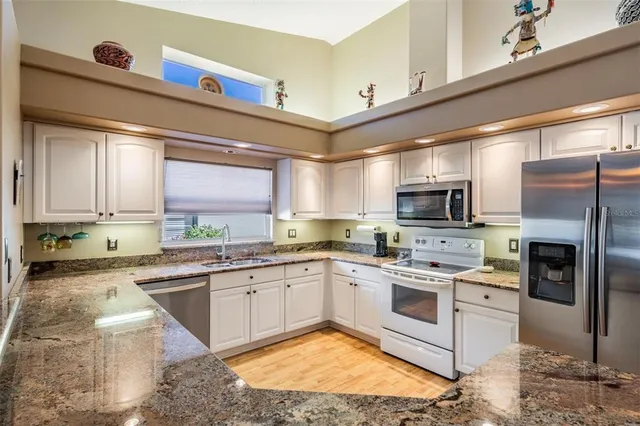 a kitchen with stainless steel appliances granite countertop a sink a stove and cabinets