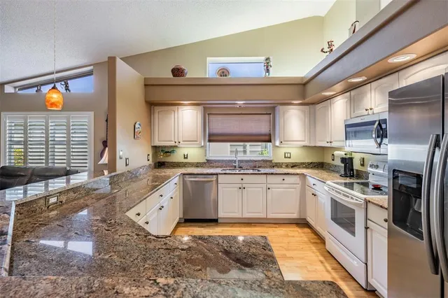 a large kitchen with stainless steel appliances granite countertop a stove a sink and a microwave