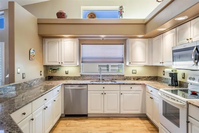 a kitchen with granite countertop white cabinets and white appliances