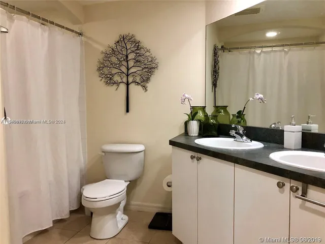 a bathroom with a granite countertop sink a toilet and a mirror