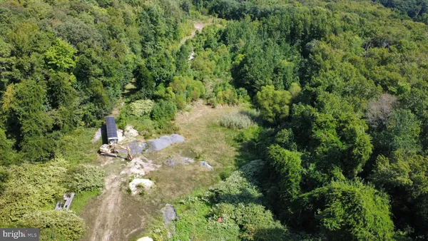 an aerial view of residential house with outdoor space and trees all around