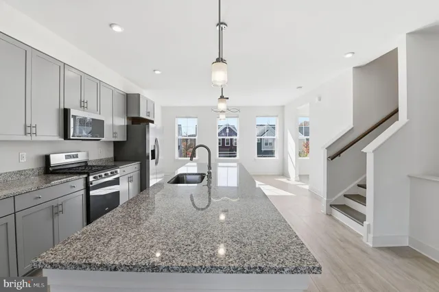 a kitchen with stainless steel appliances granite countertop a refrigerator a stove top oven a sink dishwasher and white cabinets with wooden floor