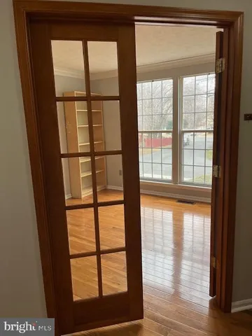 a view of an empty room with wooden floor and a window