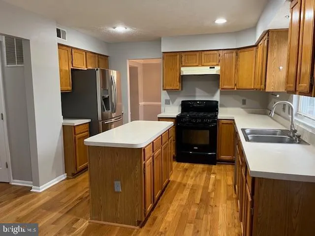 a kitchen with a refrigerator a sink and wooden cabinets