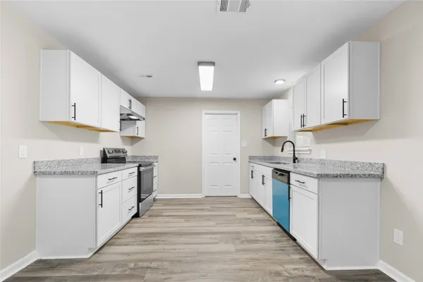 a kitchen with granite countertop a stove and a white cabinets