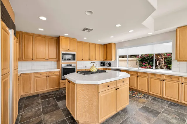 a kitchen with granite countertop a sink stove top oven and cabinets