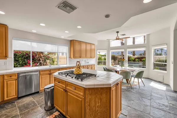 a kitchen with a stove a sink a kitchen island with chairs and wooden cabinets