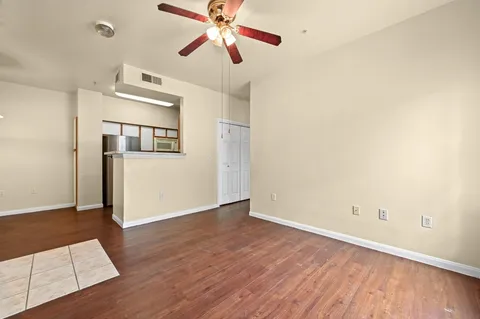 an empty room with wooden floor fan and windows