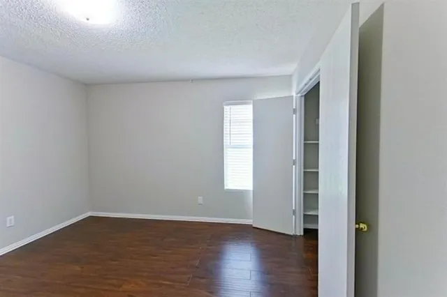 a view of an empty room with wooden floor and window