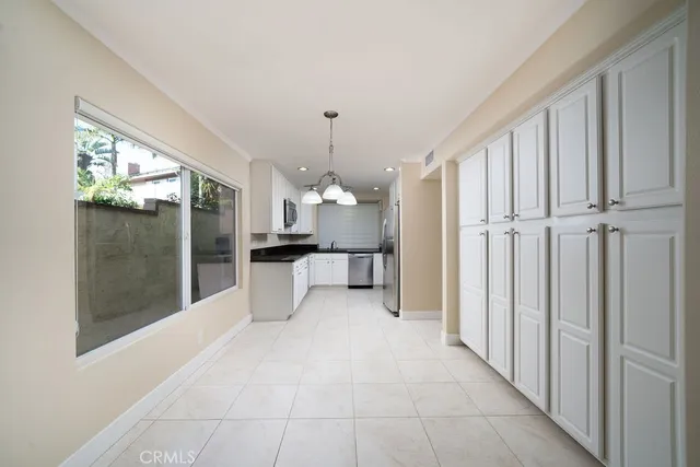 a view of an empty room with kitchen and a window