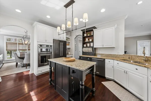 a kitchen with stainless steel appliances granite countertop a stove a sink a refrigerator and a oven with wooden floor