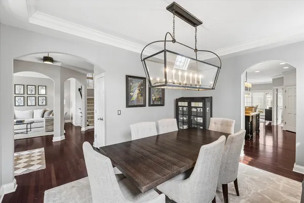 a dining room with wooden floor a chandelier a wooden table and chairs