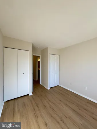 a view of an empty room with wooden floor and closet
