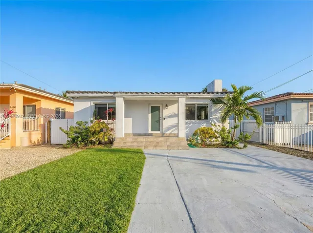a front view of a house with a yard and potted plants