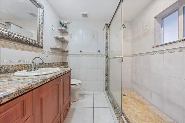 a bathroom with a granite countertop sink a toilet and shower