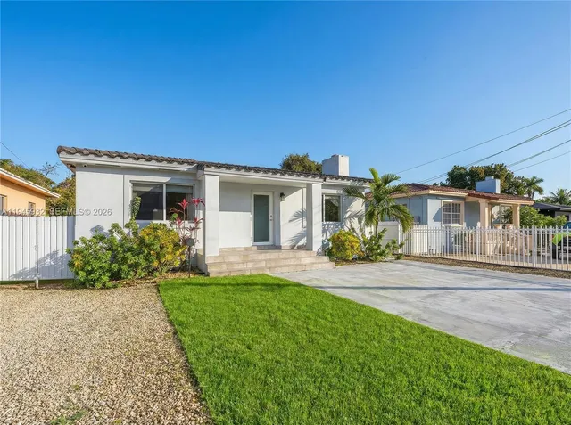 a front view of a house with a yard and potted plants